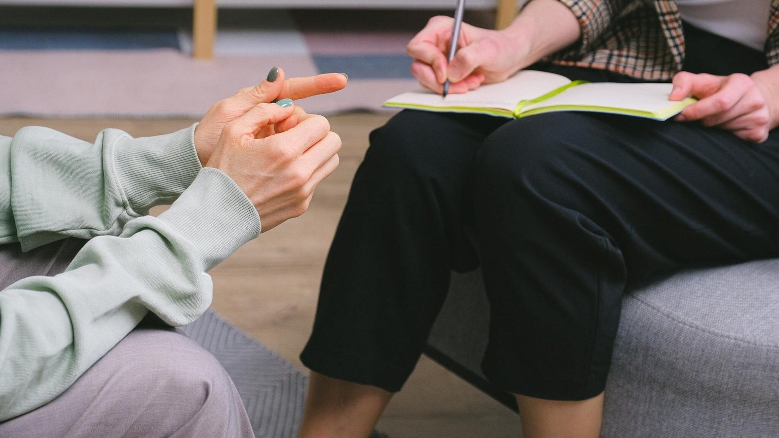 Anonymous female therapist and client sitting in armchairs during session in modern office